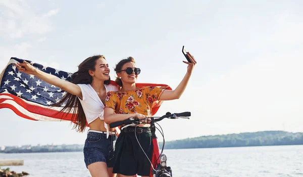 Dvě Vlastenecké Veselé Ženy Motorkou Vlajkou Usa Rukou Dělá Selfie — Stock fotografie