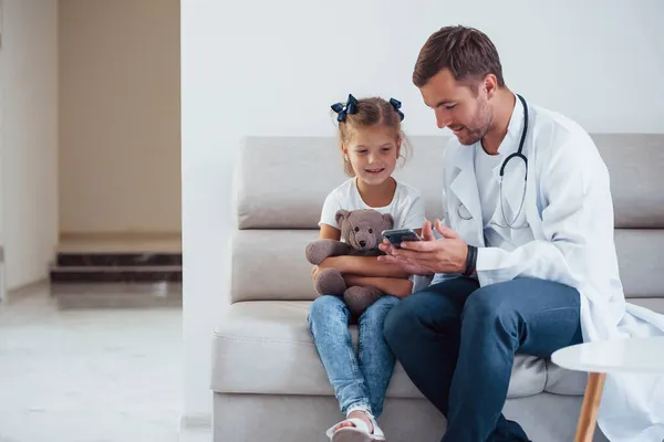 Männlicher Arzt Weißer Uniform Sitzt Mit Kleinem Mädchen Der Klinik — Stockfoto