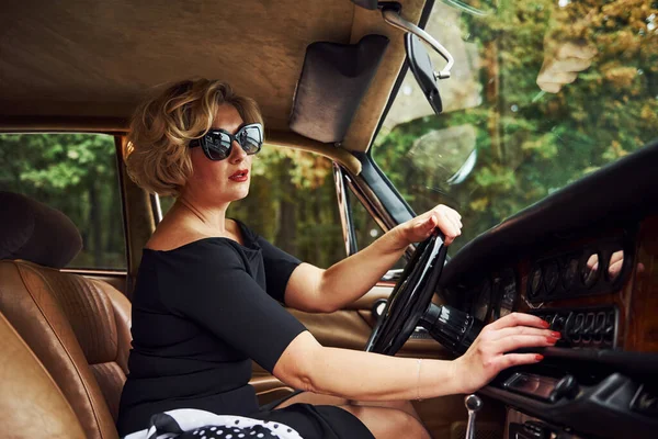 Mulher Loira Óculos Sol Vestido Preto Senta Velho Carro Clássico — Fotografia de Stock