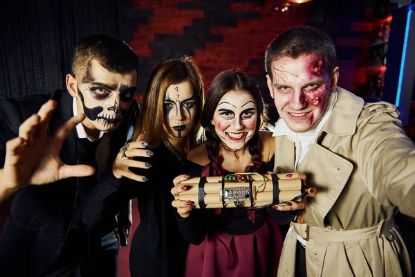 Friends with bomb in hands is on the thematic halloween party in scary makeup and costumes.