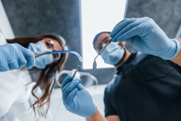 Male and female dentists working in the office together. First person view.