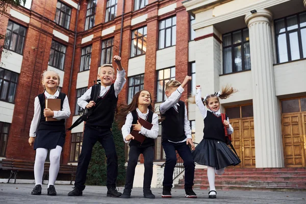 Grupp Barn Skolan Uniform Hoppa Och Kul Utomhus Tillsammans Nära — Stockfoto