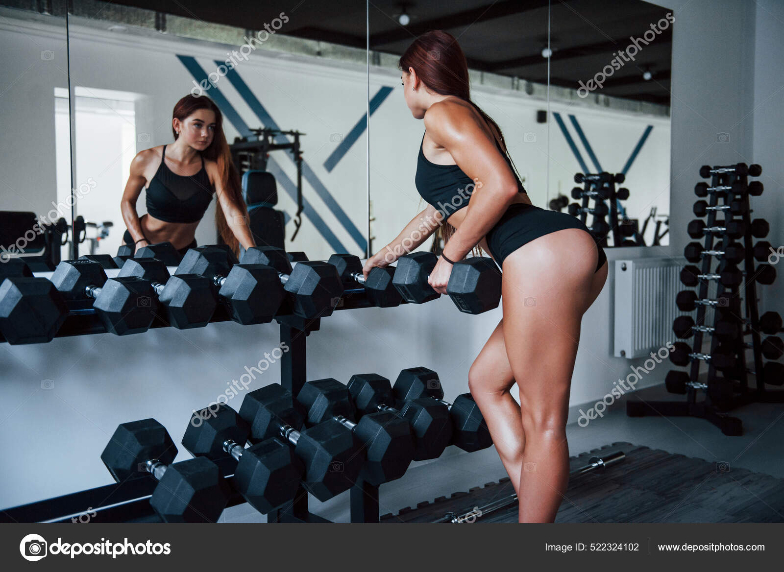 Woman in black sportive clothes have exercise with dumbbells in