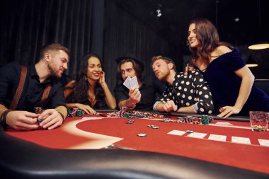 Kumarhanede birlikte poker oynayan bir grup zarif genç..