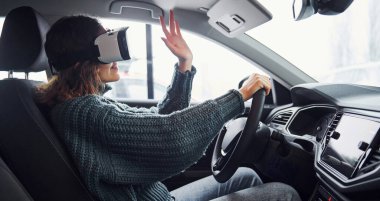 Modern arabanın içinde oturan sanal gerçeklik gözlüklü kadının yan görüntüsü..