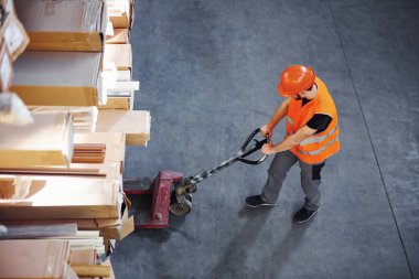 Depoda palet kamyonu süren üniformalı genç bir adamın en iyi görüntüsü..