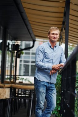 Gündüz vakti kafede duran kot pantolonlu adamın ön görüntüsü..