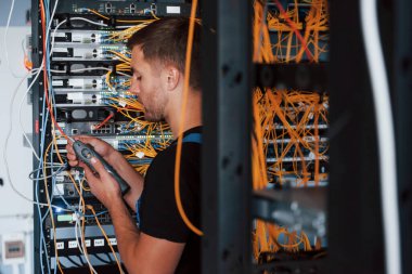 Üniformalı genç adam sunucu odasında internet teçhizatı ve kablolarla çalışıyor..