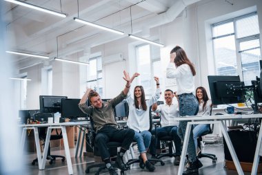 Bilgisayarların yanındaki modern ofiste insanlar konuşuyor ve birlikte çalışıyorlar..