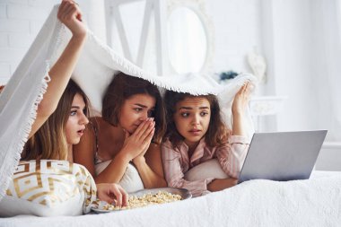 Korku filmi izliyorum. Mutlu bayan arkadaşlar yatak odasında pijama partisinde iyi vakit geçiriyorlar..