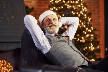 Gri saçlı, sakallı, ceketli ve beyaz gömlekli son sınıf öğrencisinin portresi süslü Noel odasında..