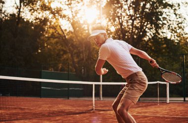 Güzel güneş ışığı. Spor elbiseli genç tenisçi dışarıda..