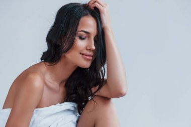 Yatağın üzerinde beyaz havluyla oturan güzel esmer kızın portresi..