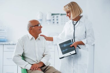 Kıdemli adamın klinikte kadın doktorun muayenesi var..