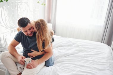 Bir bardak içki. Genç evli çiftler gündüzleri yatak odasında vakit geçirirler..