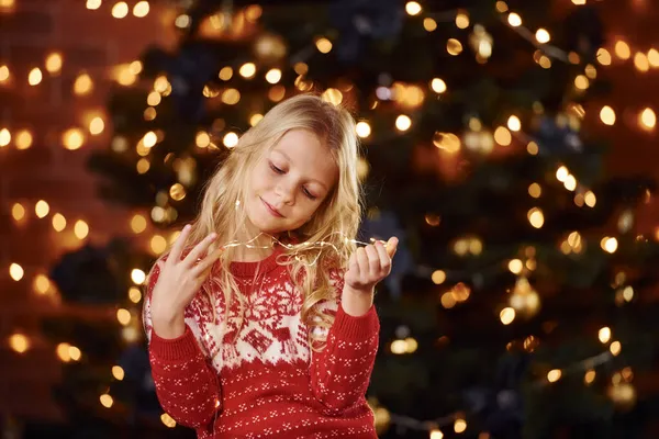 在靠近圣诞树的地方 可爱的小女孩在室内庆祝新年 — 图库照片