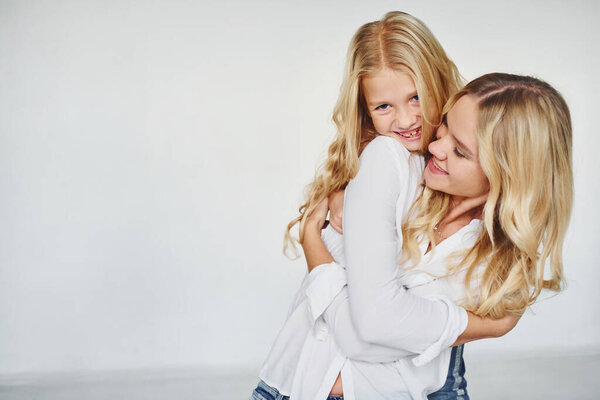 Mother with her daughter have fun together in the studio with white background.