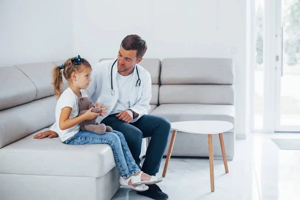 Médico Masculino Uniforme Blanco Sienta Clínica Con Una Niña —  Fotos de Stock