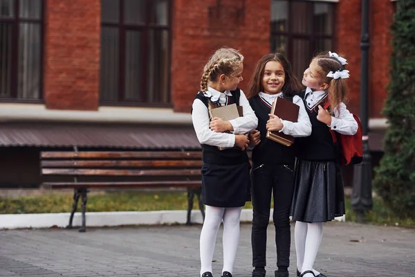 教育棟の近くにある屋外の学校の制服を着た女性の子供たちのグループ — ストック写真
