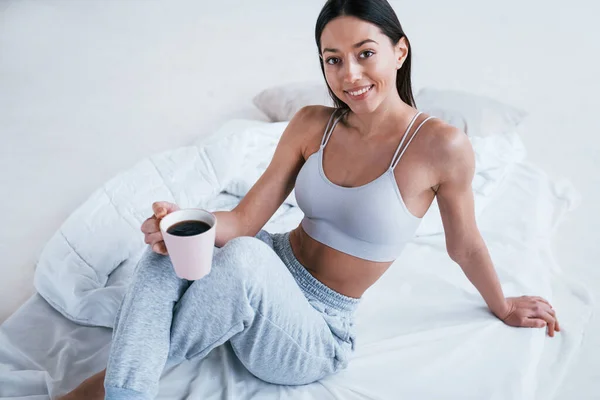 Positivo Donna Sorridente Abiti Sportivi Siede Studio Con Tazza Bevanda — Foto Stock