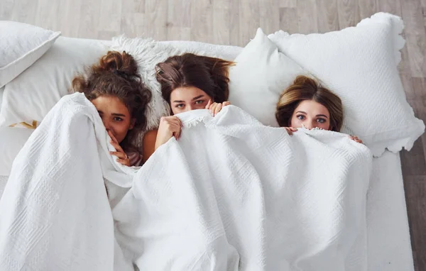 躲在毯子下面在睡房的睡衣派对上玩得开心的女性朋友 — 图库照片