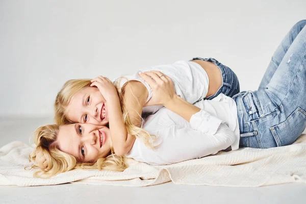 彼女の娘と一緒に母親は白い背景を持つスタジオで地面にあります — ストック写真