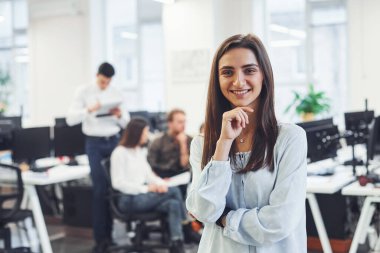 Modern ofiste birlikte çalışan genç iş adamlarının önünde duran pozitif kadın..