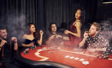 Kumarhanede birlikte poker oynayan bir grup zarif genç..