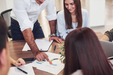 Masanın yanında oturuyor. Modern ofiste birlikte çalışan genç iş adamları..