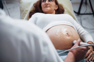 Erkek doktor hastanede hamile bir kadın için ultrason yapıyor..