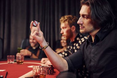 Kumarhanede birlikte poker oynayan bir grup zarif genç..