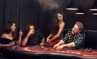 Kumarhanede birlikte poker oynayan bir grup zarif genç..