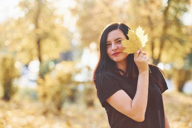 Güzel sonbahar parkında yapraklarla eğlenen esmerin portresi..