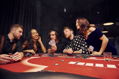 Kumarhanede birlikte poker oynayan bir grup zarif genç..