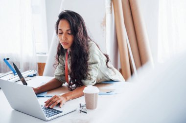 Laptop ve bir bardak içki masada. Güzel bayan işçi dikiş fabrikasında..