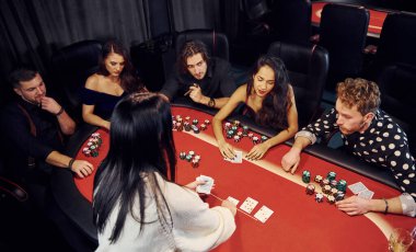 Kumarhanede birlikte poker oynayan bir grup zarif genç..