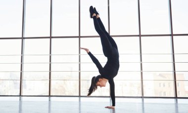 Spor giyim sektöründe pencereye karşı atletik numaralar yapan kadınların yan görünüşü..