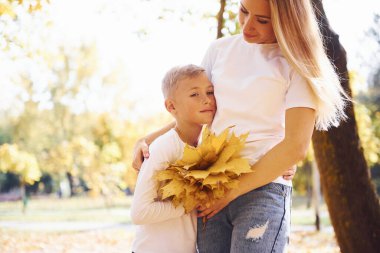 Anne ve oğlu güneşli bir günde güzel bir sonbahar parkında dinleniyorlar..
