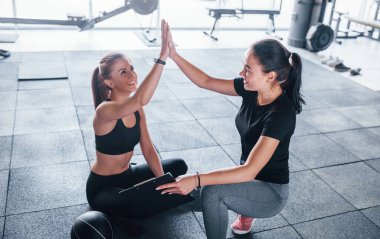 Not defteri olan kadın kişisel antrenör kadına beşlik çakıyor..