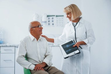 Kıdemli adamın klinikte kadın doktorun muayenesi var..