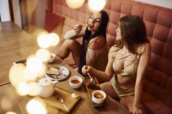 Dos Mujeres Jóvenes Sexy Sienta Sofá Cerca Mesa Con Comida —  Fotos de Stock