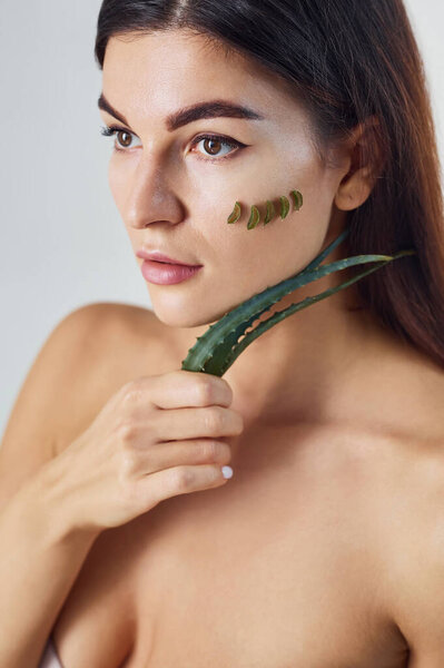 Голая женщина в студии на белом фоне с алоэ верой.