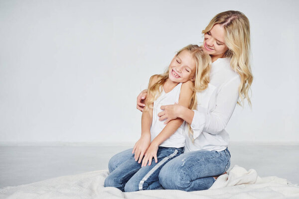 Closeness of the people. Mother with her daughter together in the studio with white background.