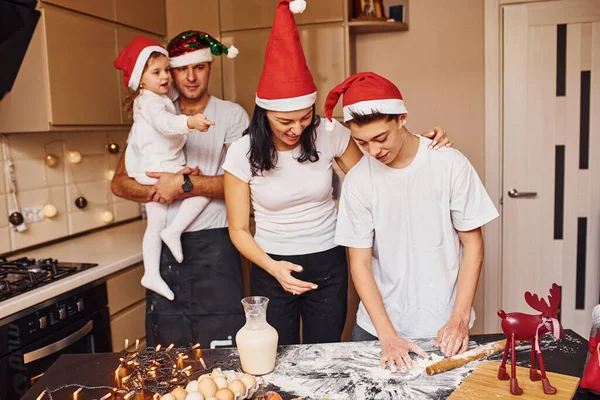 クリスマスの帽子の祭りの家族はキッチンで楽しみ 食べ物を準備する — ストック写真