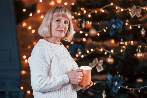 Fröhliche Seniorin Steht Mit Getränk Weihnachtlich Dekorierten Raum — Stockfoto