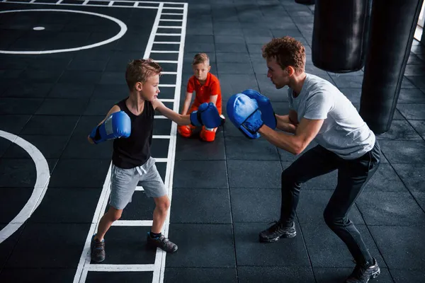 조련사는 어린이들에게 체육관에서 권투를 가르친다 — 스톡 사진