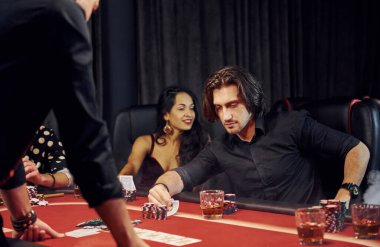 Bir bardak içkiyle. Kumarhanede birlikte poker oynayan bir grup zarif genç..