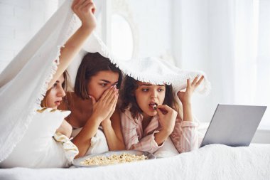 Korku filmi izliyorum. Mutlu bayan arkadaşlar yatak odasında pijama partisinde iyi vakit geçiriyorlar..