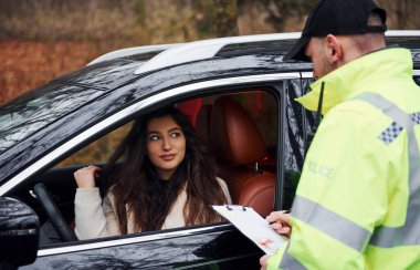 Yeşil üniformalı bir polis memuru, yolda aracını kontrol ediyor..