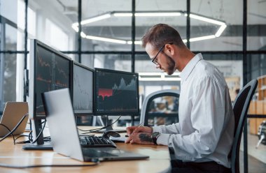 Resmi giyinmiş erkek borsacı ofiste finans piyasasında çalışıyor..